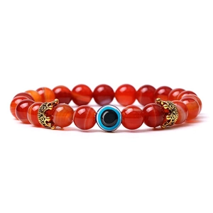 Detail of red agate beaded bracelet featuring a gold crown and blue evil eye charm