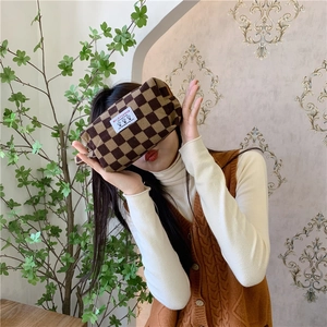 Trousse de maquillage en velours côtelé à damier marron et beige tenue par une personne