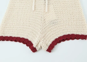 Detail of crochet shorts with cream knit texture and burgundy scalloped wavy edges