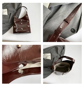 Detail view of red-brown leather handbag showing metal studs and magnetic closure
