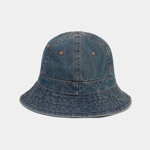 Détail d'un bob en jean bleu foncé avec coutures contrastées orange et œillets en métal