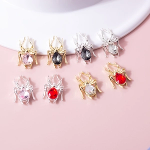 Detailed view of 3D spider nail charms with teardrop rhinestones in various colors