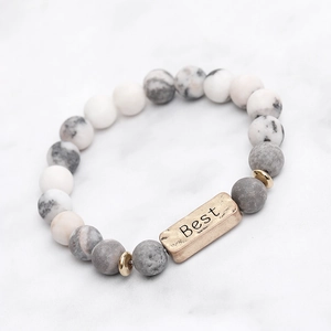 Macro-opname van stenen yoga-armband met gouden staaf gegraveerd met de tekst Best