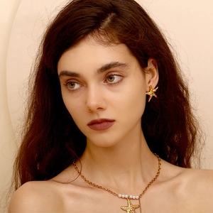 Close-up of 18K gold plated starfish earrings and pearl necklace on a female model