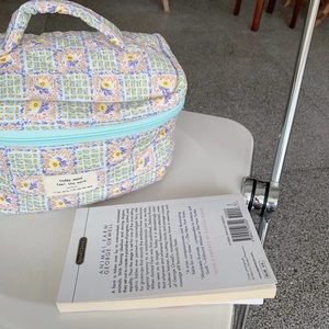 Détail d'une trousse de maquillage fleurie matelassée avec fermeture éclair et poignée