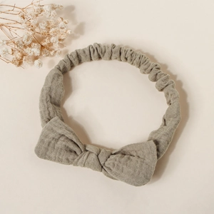 Detail view of sage green cotton bow headband with elastic strap and textured fabric