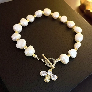 Detail of baroque pearl bracelet with a gold bee pendant and toggle clasp closure