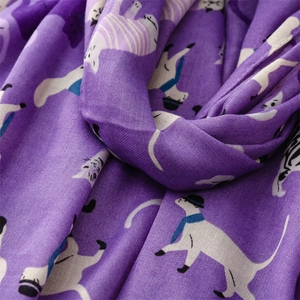 Detail of soft purple scarf fabric featuring cute white cartoon cat patterns with blue scarves