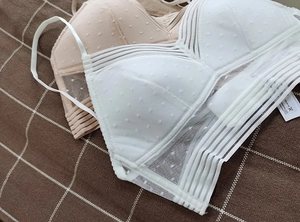 Detail of white and apricot backless bras with dotted mesh and striped elastic bands