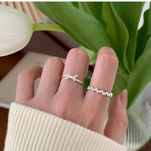 Silver bow knot ring and beaded bubble band shown against a soft floral background