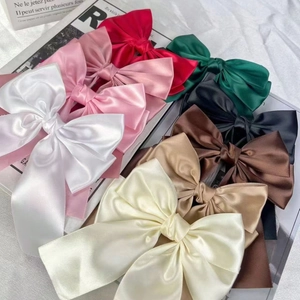 Elegant set of colorful satin bow hair clips displayed on minimalist French paper