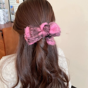 Detail of a pink and black flocking bow hair clip styled on wavy dark brown hair