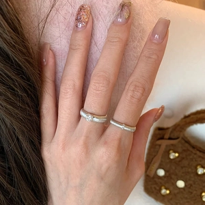 Luxury woven metal ring set with diamonds and brushed texture on model's finger