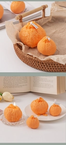 Vela aromática con forma de naranja realista y textura de piel sobre una bandeja