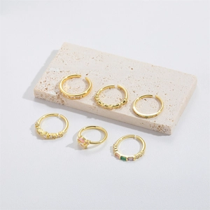 Detailed close-up of six gold adjustable open rings with colorful gemstone inlays