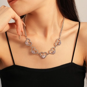 Close-up of pink heart pendant necklace on neck featuring silver linked hollow hearts