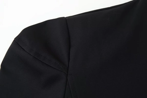 Detail of high-quality shoulder stitching on a black V-neck jacket with premium texture