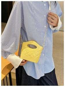 Dettaglio della mini borsa a secchiello in PVC giallo con catena dorata su modella