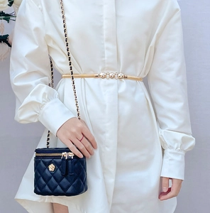 Close-up of a gold metal elastic waist chain styled on a white shirt dress for women
