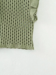 Detailed macro view of green knit fabric with hollow mesh texture and ruffle sleeve accents