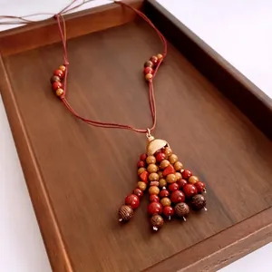 Bohemian vintage tassel necklace with red and brown wooden beads on wooden tray