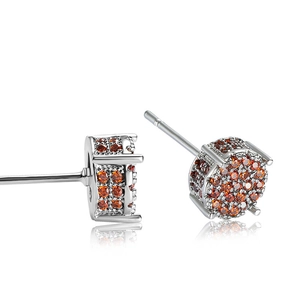 Close-up of hip hop style ear studs featuring micro-paved amber cubic zirconia on silver metal