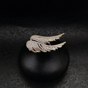 Detail shot of golden wing brooch with layered feathers and shimmering rhinestones