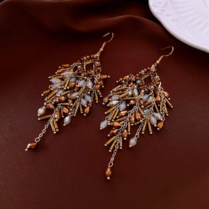 Macro view of bohemian crystal fringe earrings with beads on dark velvet fabric