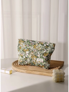 Floral makeup pouch with green flower pattern on a minimalist wooden display stand
