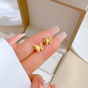 Detailed view of gold butterfly stud earrings featuring matte and polished finishes