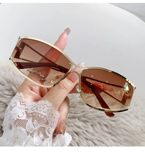 Close-up of futuristic Y2K rectangular sunglasses with gold metal frame and brown lenses
