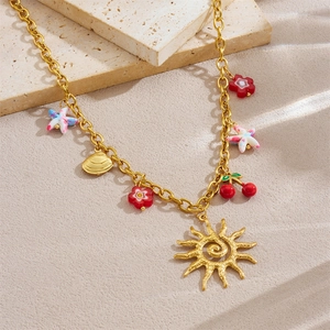 Halskette aus Gold-Edelstahl mit Sonnen- Blumen- und Seesternanhängern auf Strandstein