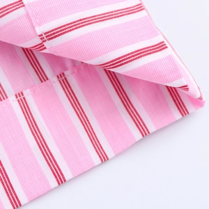 Detailed macro shot of striped fabric with precise stitching on pink and red woven cotton