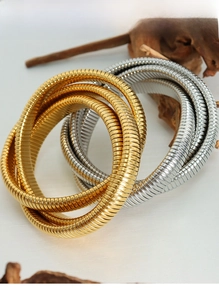 Macro shot of gold and silver coiled snake-bone bracelets with polished metallic texture