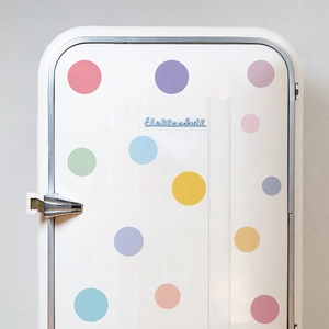 Close-up of colorful round dot stickers applied on a white vintage refrigerator door