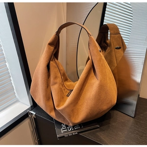 Close-up of brown suede tote bag with metal zipper in soft indoor window lighting