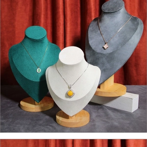 Velvet necklace display busts in green, white, and gray with round wooden bases