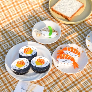 Detailed overhead view of assorted sushi-shaped acetate hair claws on a yellow plaid cloth