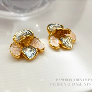 Macro shot of 3D floral stud earrings with enamel petals on a ceramic tray