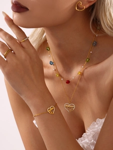 Model draagt gouden MAMMA hart kettingset met kleurrijke kralen en zirkoon accenten