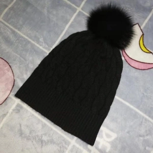 Detail der Strickstruktur und des schwarzen Bommels der dicken Wintermütze