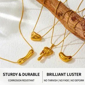 Detailed shot of irregular gold lava heart pendants on snake chains over a wood prop