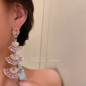 Luxurious gold fan-shaped drop earrings with purple crystals and diamonds on model