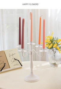 Detail of white 5-arm metal candelabra with morandi colored taper candles and mimosa