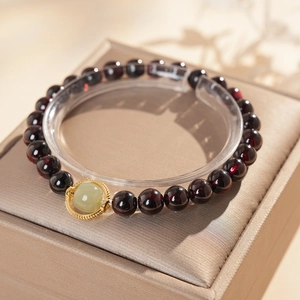 Détail d'un bracelet en grenat avec un centre en jade Hetian vert et cadre doré