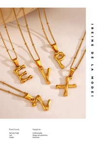 Gros plan de pendentifs alphabet dorés avec texture bambou sur des chaînes fines