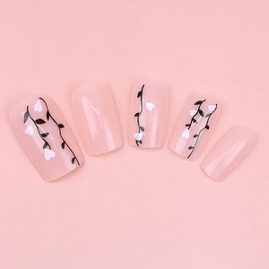Glossy pink press-on nails featuring elegant black vine patterns and white heart accents