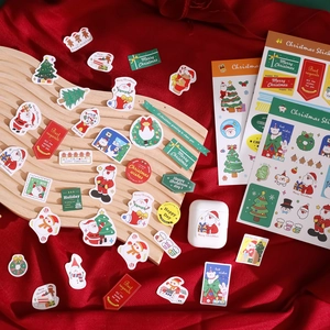 Christmas themed decorative stickers with Santa and trees on a rustic wooden tray