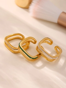 Detailed view of three gold-plated stackable rings with zircon, emerald, and pearls