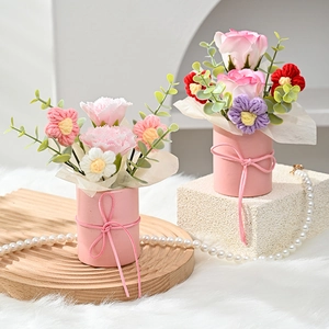 Detailed view of handmade knitted carnation bouquets in pink gift pots with ribbons